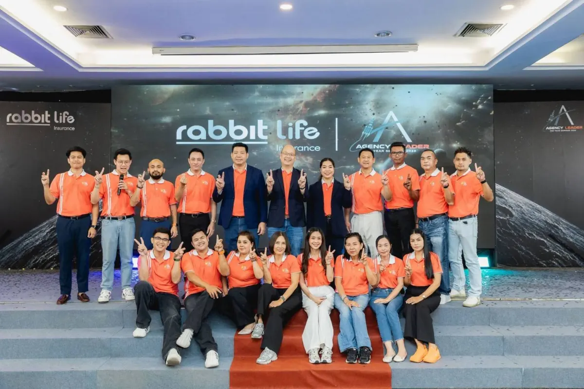 ทีมตัวแทนแรบบิท ไลฟ์ ในเสื้อสีส้ม ถ่ายรูปหมู่บนเวทีงานสัมมนา Agency Leader